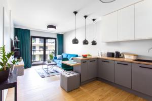 una cucina a pianta aperta e un soggiorno con divano blu di Apartament Gardenia Sea&Sun DZIWNÓW PRZY PLAŻY a Dziwnów