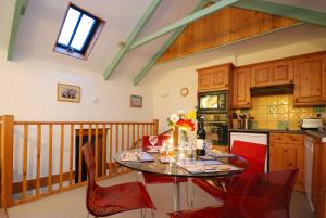 uma cozinha com uma mesa e cadeiras vermelhas num quarto em Granary at Trewerry Cottages - Away from it all, close to everywhere em Newquay