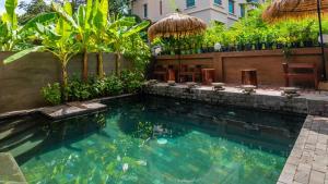 a swimming pool in a yard with chairs and trees at Maison Model d'Angkor in Siem Reap