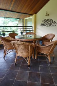 a dining room with a glass table and wicker chairs at Araiya Palampur in Pālampur