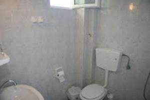 a white bathroom with a toilet and a sink at Daniel Hotel in Kalamaki