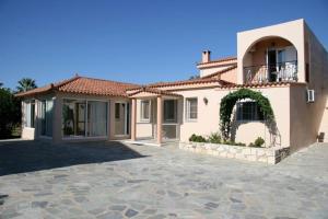 a large white house with a stone driveway at Daniel Hotel in Kalamaki