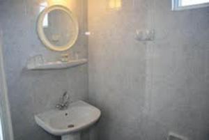 a white bathroom with a sink and a mirror at Daniel Hotel in Kalamaki