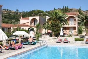 a group of people sitting in lawn chairs by a pool at Daniel Hotel in Kalamaki