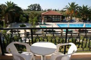 two white chairs and a table on a balcony with a pool at Daniel Hotel in Kalamaki