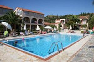 a large swimming pool in a resort with people sitting around it at Daniel Hotel in Kalamaki