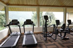 a gym with treadmills and ellipticals in front of a window at Araiya Palampur in Pālampur