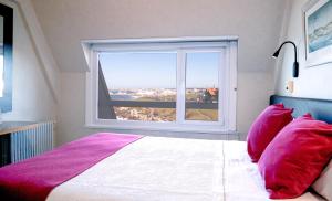 a bedroom with a bed with red pillows and a window at Hotel Las Rocas in Mar del Plata