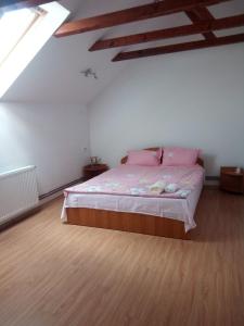 a bedroom with a bed with pink sheets on it at Pensiunea Valea Beiului in Socolari