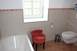 a bathroom with a tub and a toilet and a red chair at Ferienhaus Sprink Vulkaneifel in Strohn +28 photos