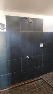 a bathroom with a shower with a black tile wall at Sunset Beach Bungalow in Gili Meno