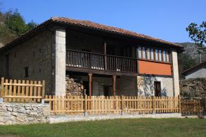 a house with a wooden fence in front of it at Hotel Rural Llerau in Taranes