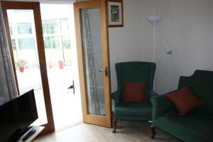 利馬瓦迪的住宿－Carrowbruagh，客厅配有两把椅子和电视