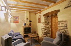 a living room with two blue chairs and a fireplace at Casa Rural El Llao Y Los Fresnos - El Urogallo in Murias de Paredes