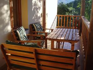 porche con 3 sillas, mesa de madera y banco en Casa Rural El Llao Y Los Fresnos - El Urogallo, en Murias de Paredes