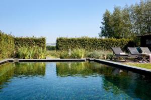 a swimming pool in a yard with two chairs next to it at Gasterie Lieve Hemel in Sevenum