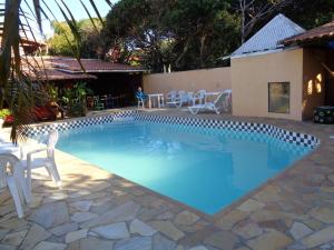 una gran piscina azul con sillas blancas alrededor. en Pousada Barcarola en Búzios