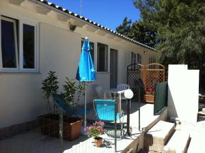 a patio with two chairs and a blue umbrella at Casa Vacanze Mari in San Vito lo Capo