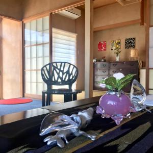 Cette chambre comprend une table avec un vase et une chaise. dans l'établissement One Rest Private House, à Naoshima