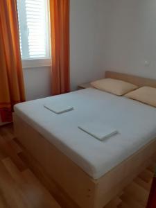 a white bed in a room with a window at Apartmani Ruža in Novalja
