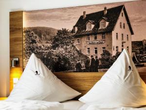 ein Bett mit zwei Kissen und ein Bild eines Hauses in der Unterkunft Hotel zum Engel in Mespelbrunn