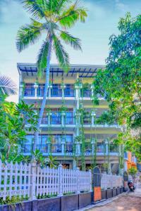 a white fence in front of a building with a palm tree at L&D Stay Inn in Hikkaduwa