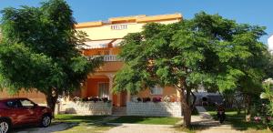 a red car parked in front of a house at Apartmani Ruža in Novalja