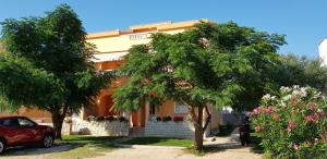 a red car parked in front of a building at Apartmani Ruža in Novalja