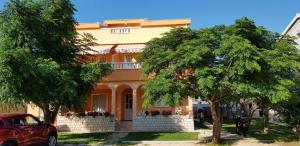 a yellow house with a tree in front of it at Apartmani Ruža in Novalja