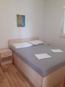 a bed in a room with a white wall at Apartmani Ruža in Novalja
