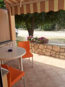 a patio with a table and chairs and a stone wall at Apartmani Ruža in Novalja