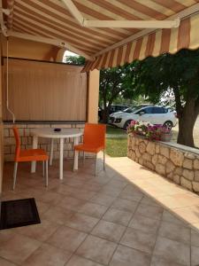 a patio with a table and chairs and a stone wall at Apartmani Ruža in Novalja