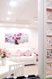 a white living room with a white couch and pink flowers at Anchor and Rose in Salerno