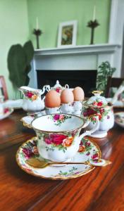 un tavolo in legno con uova in tazze da tè e piattini di Little Robin B&B a Dufftown