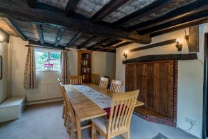a dining room with a wooden table and chairs at Yew Tree Cottage in Moulsoe
