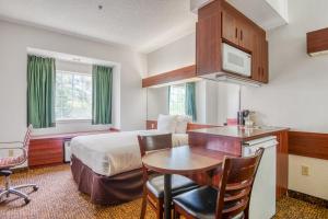 um quarto de hotel com uma cama, uma secretária e uma mesa em Trident Inn & Suites, Baton Rouge em Baton Rouge