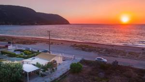 a sunset over a beach with cars parked on it at Rontos House, seaside in Lefkada