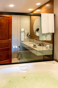 a bathroom with a tub and a sink at Hotel Ferradura Resort in Búzios