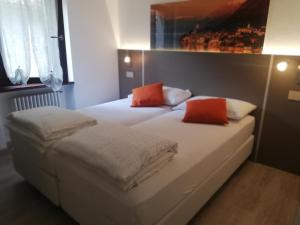 een slaapkamer met 2 bedden met witte lakens en oranje kussens bij Cà alla Pòssa in Malcesine +13 foto's