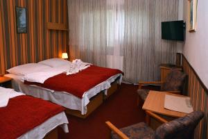 a hotel room with two beds and a table and chairs at Penzion Horalka in Hlinsko