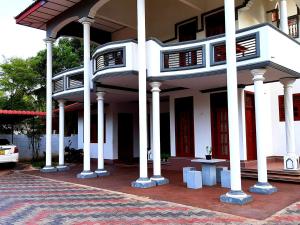 a white building with white columns and red doors at A and D Holiday Inn in Anuradhapura