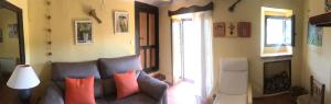 a living room with a gray couch with colorful pillows at Casa Rural Las Dalias con Hidromasaje in Villafranca del Cid