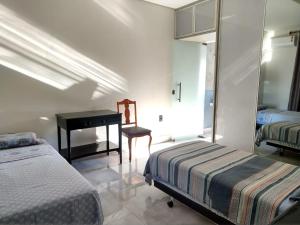 um quarto com 2 camas, uma mesa e uma cadeira em Casa da Lúcia em Uberlândia
