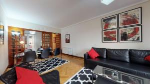 sala de estar con sofá de cuero negro y almohadas rojas en Apartamento Plaza Del Castillo, en Pamplona