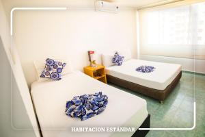 a room with two beds with blue pillows on them at Hotel Portobahia Santa Marta Rodadero in Santa Marta