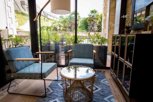 two chairs and a coffee table in a room with windows at La Suite d'Elisabeth in Sarlat-la-Canéda