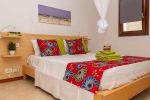 Schlafzimmer mit einem Bett mit roten und grünen Kissen in der Unterkunft Ca Bonita in Sal Rei