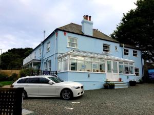 um carro branco estacionado em frente a uma casa azul em Channel View Guest House em Stoke Fleming