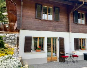 a house with red chairs and a table in front of it at One Bedroom with mountain and garden view ground floor of Chalet Solaria in Zweisimmen