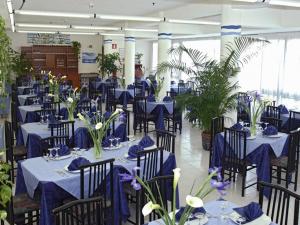 a dining room with blue tables and chairs and plants at Hotel Le Palme in Sabaudia